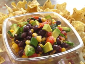 Close up view of poor man's caviar, salad with avocado, black beans, corn and tomatoes in a bowl, served with tortilla chips