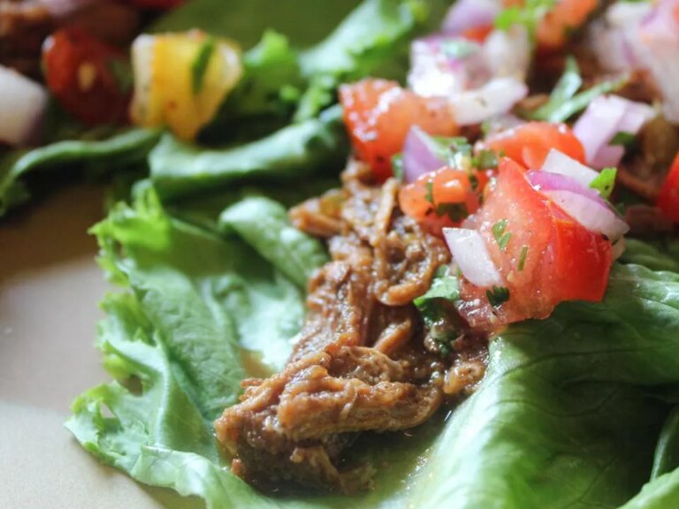 Close up view of shredded mexican beef with salsa on lettuce wraps on a plate