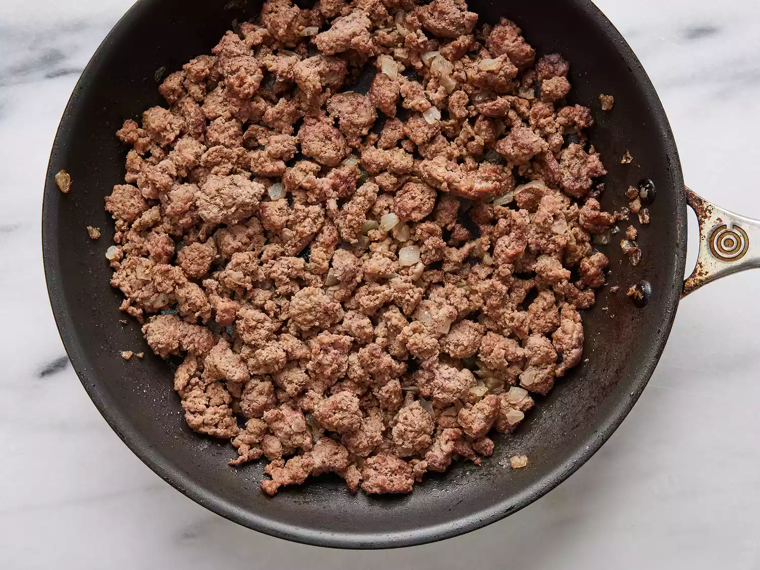Ground beef and onions cooking on a skillet. 