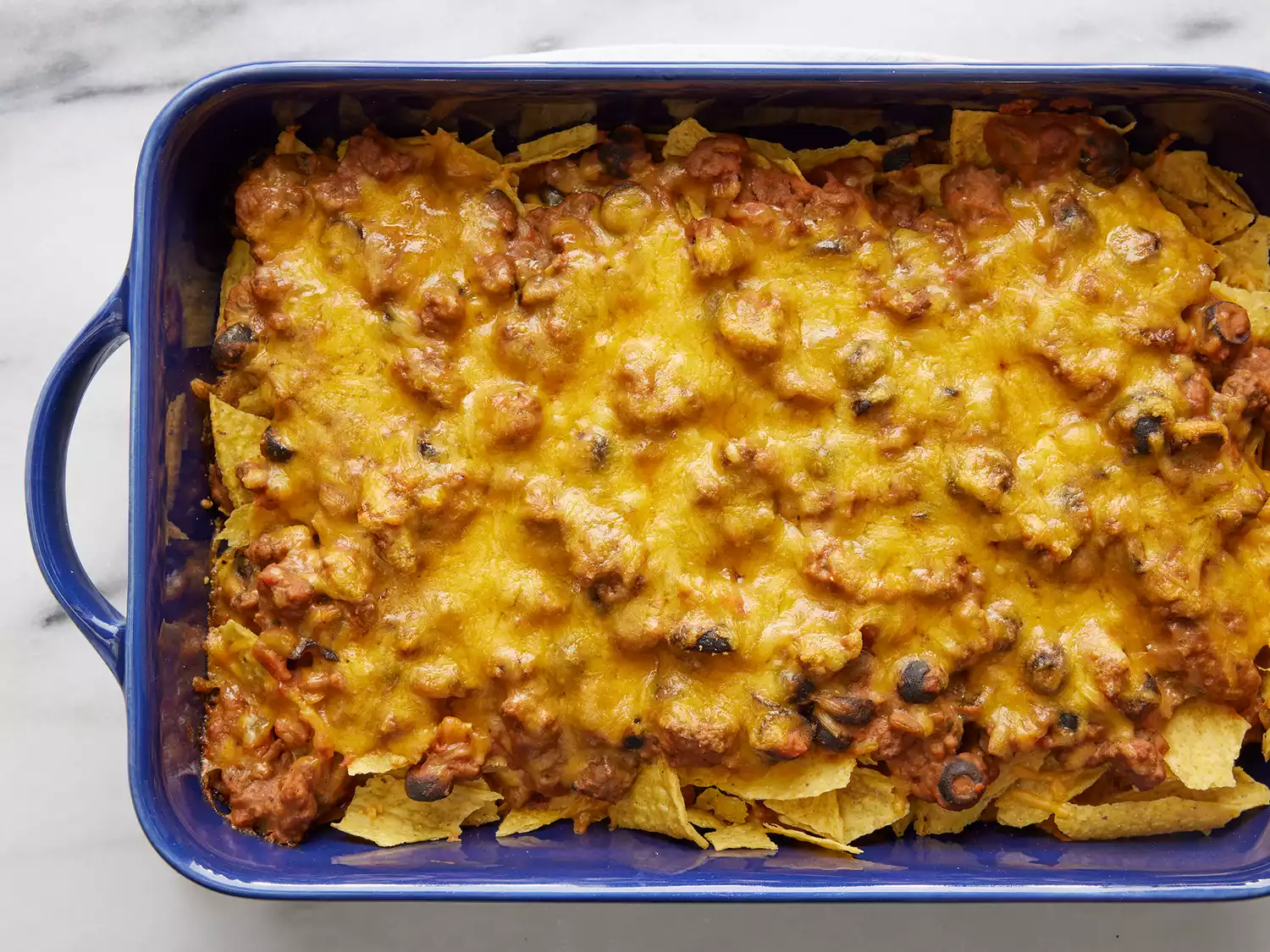 Overhead of a cooked taco casserole in a blue casserole dish. 