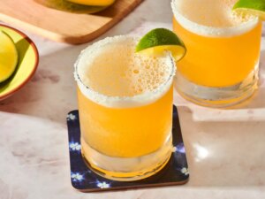 Two mango margaritas in glasses with lime wedges