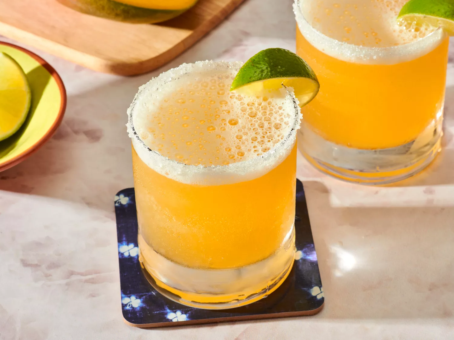 Two mango margaritas in glasses with lime wedges