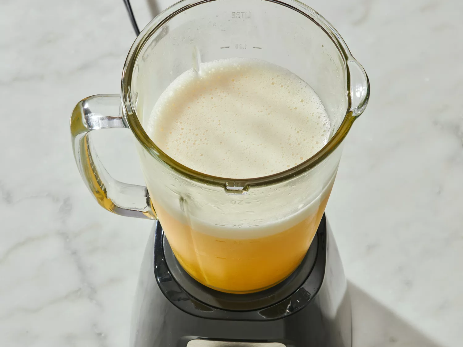 Blender filled with a blended mango beverage on a countertop