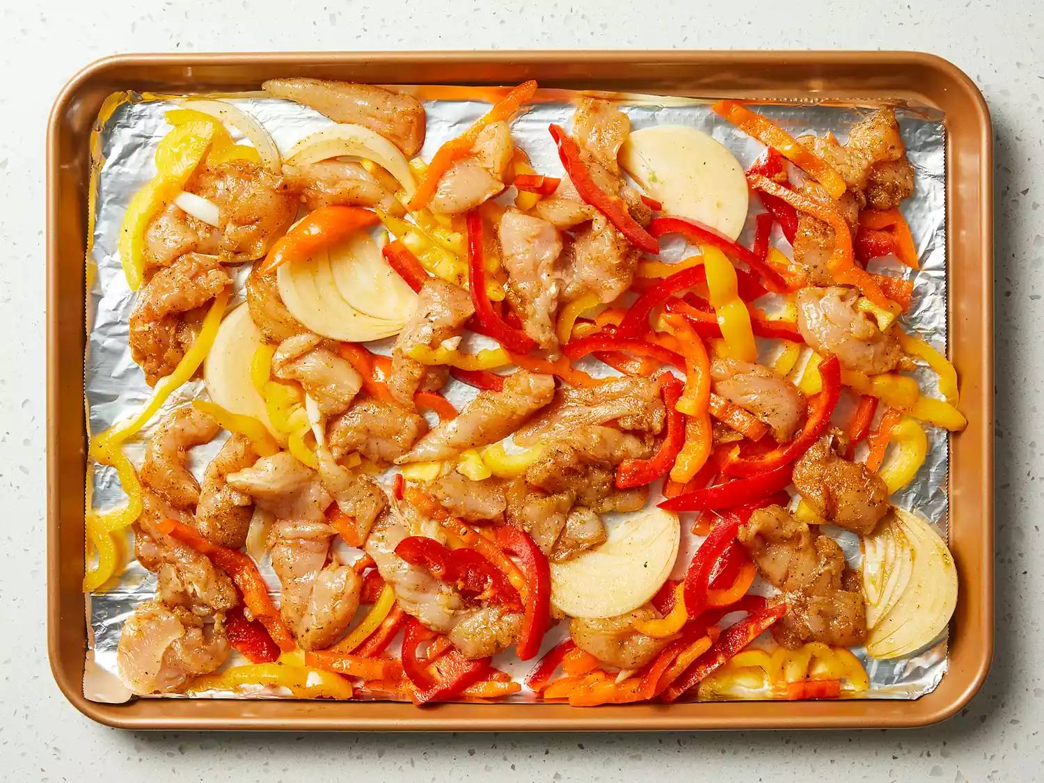 an overhead shot of marinaded chicken fajitas laid out on a sheet pan