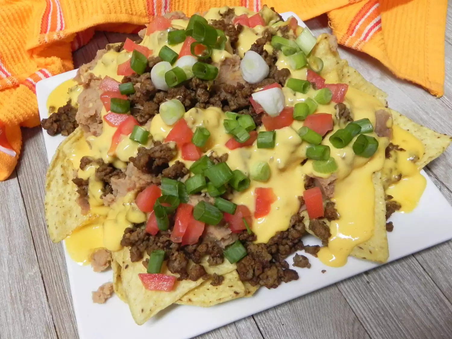 Ground beef taco nachos topped with cheese, tomatoes and green onions