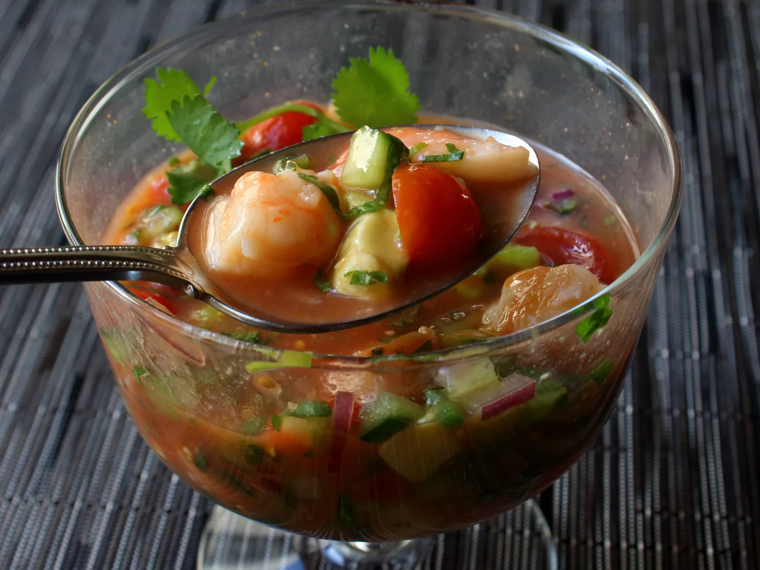 Closeup of a spoonful of chef john's mexican style shrimp cocktail scooped from a glass dish