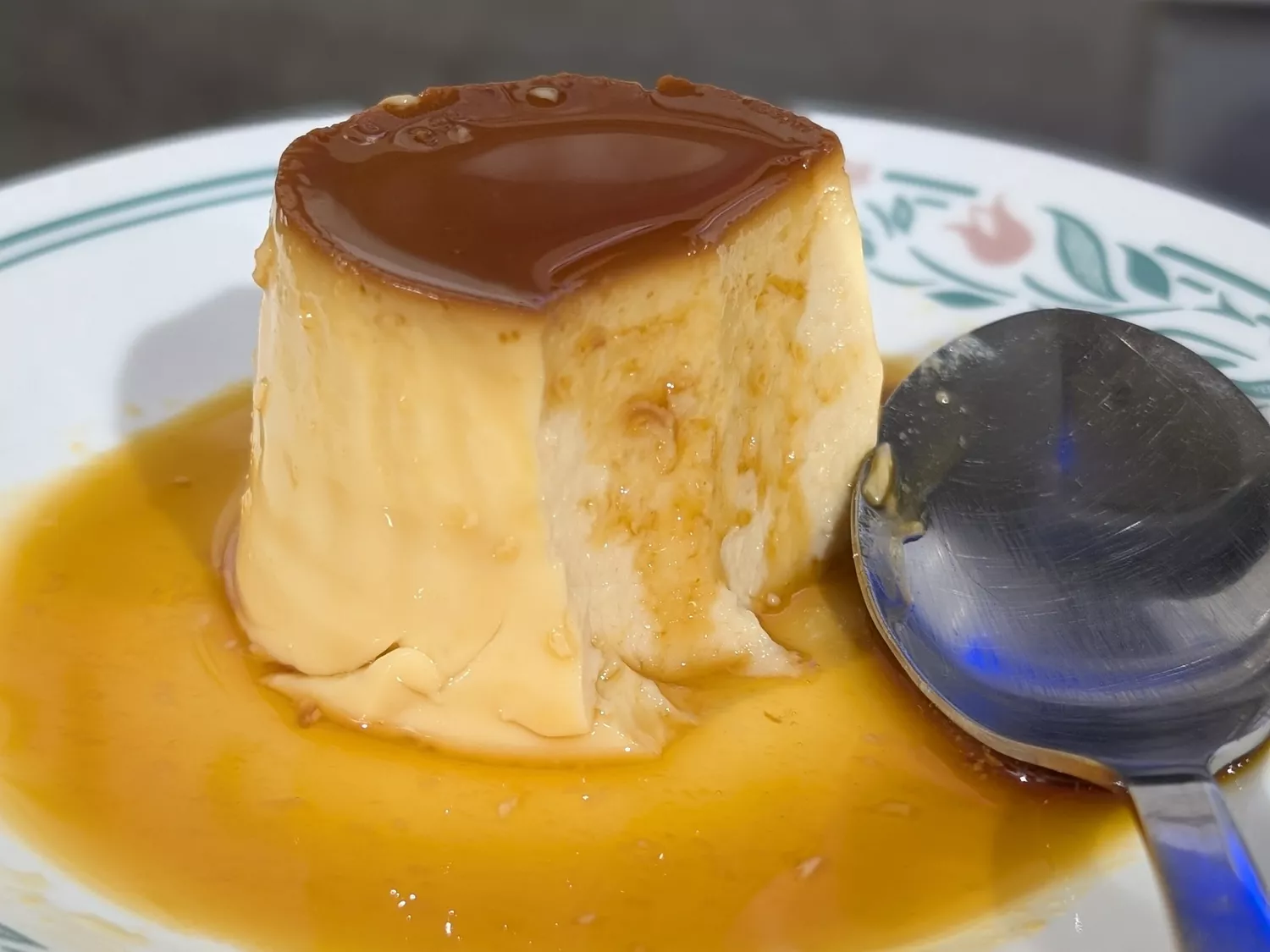Flan with caramel sauce and spoon on plate
