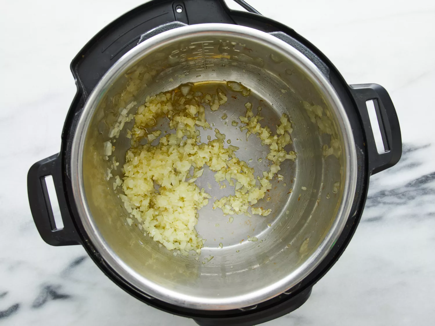 Onions cooking in pressure cooker until fragrant. 