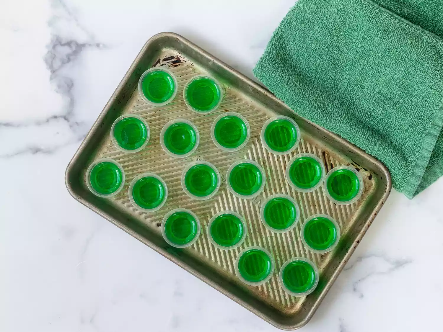 Tray with green jello shots in small cups, green cloth on the side
