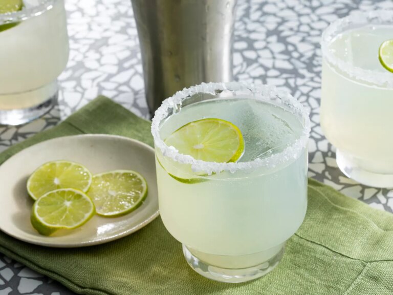 Mid angle looking at a glass of margarita garnished with lime slices
