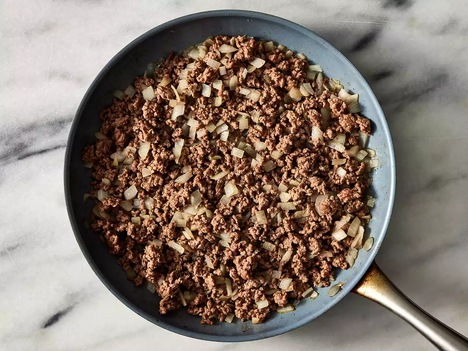Beef and onion cooking in a skillet until beef is done and onions are tender.