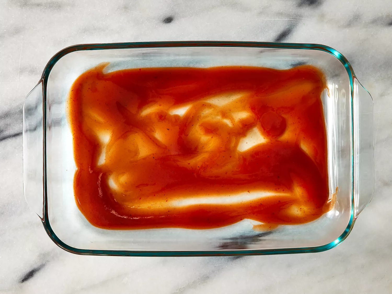 1/4 cup of enchilada sauce poured into baking dish.