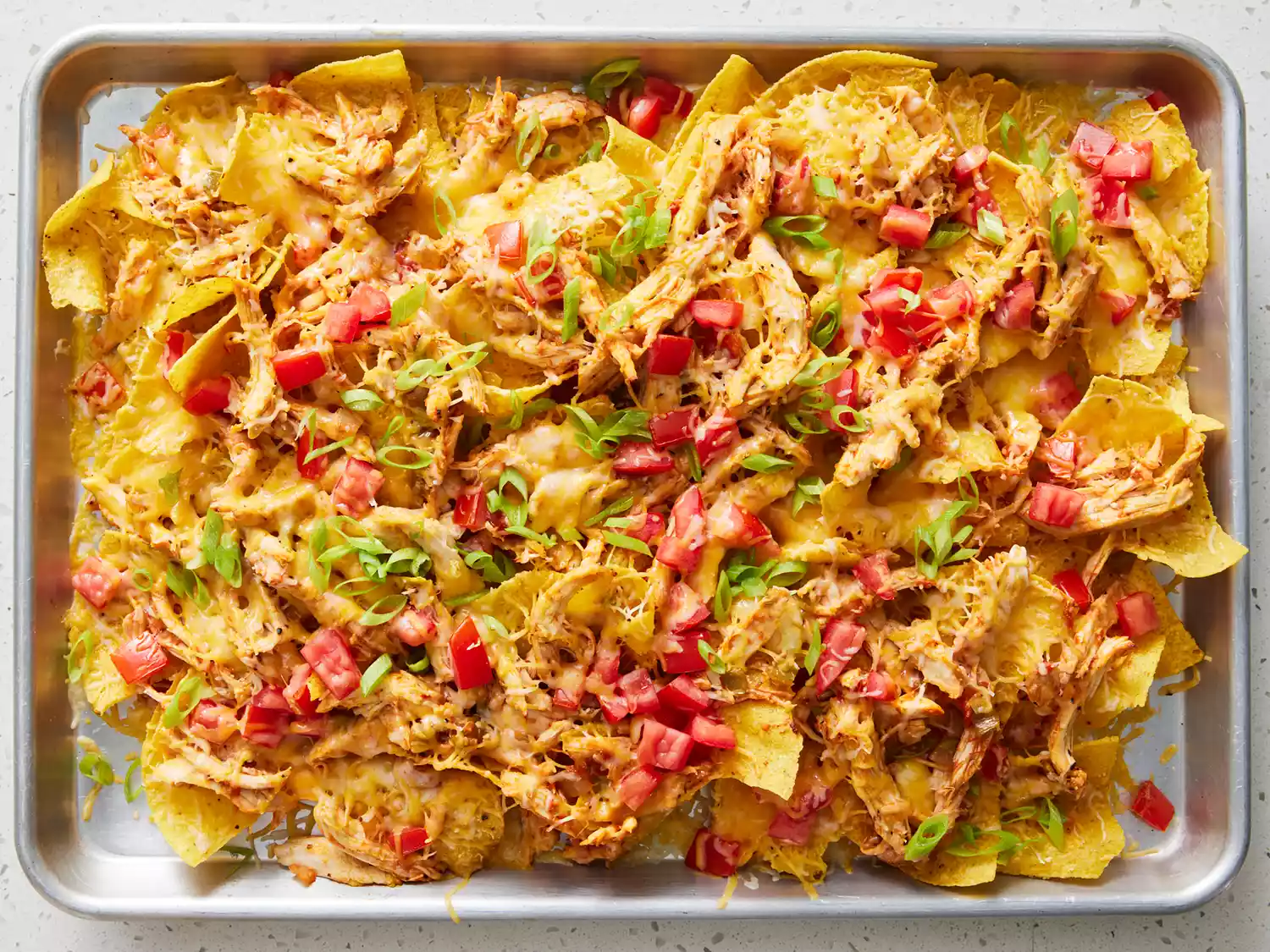 restaurant style nachos fresh out of the oven and topped with green onions 