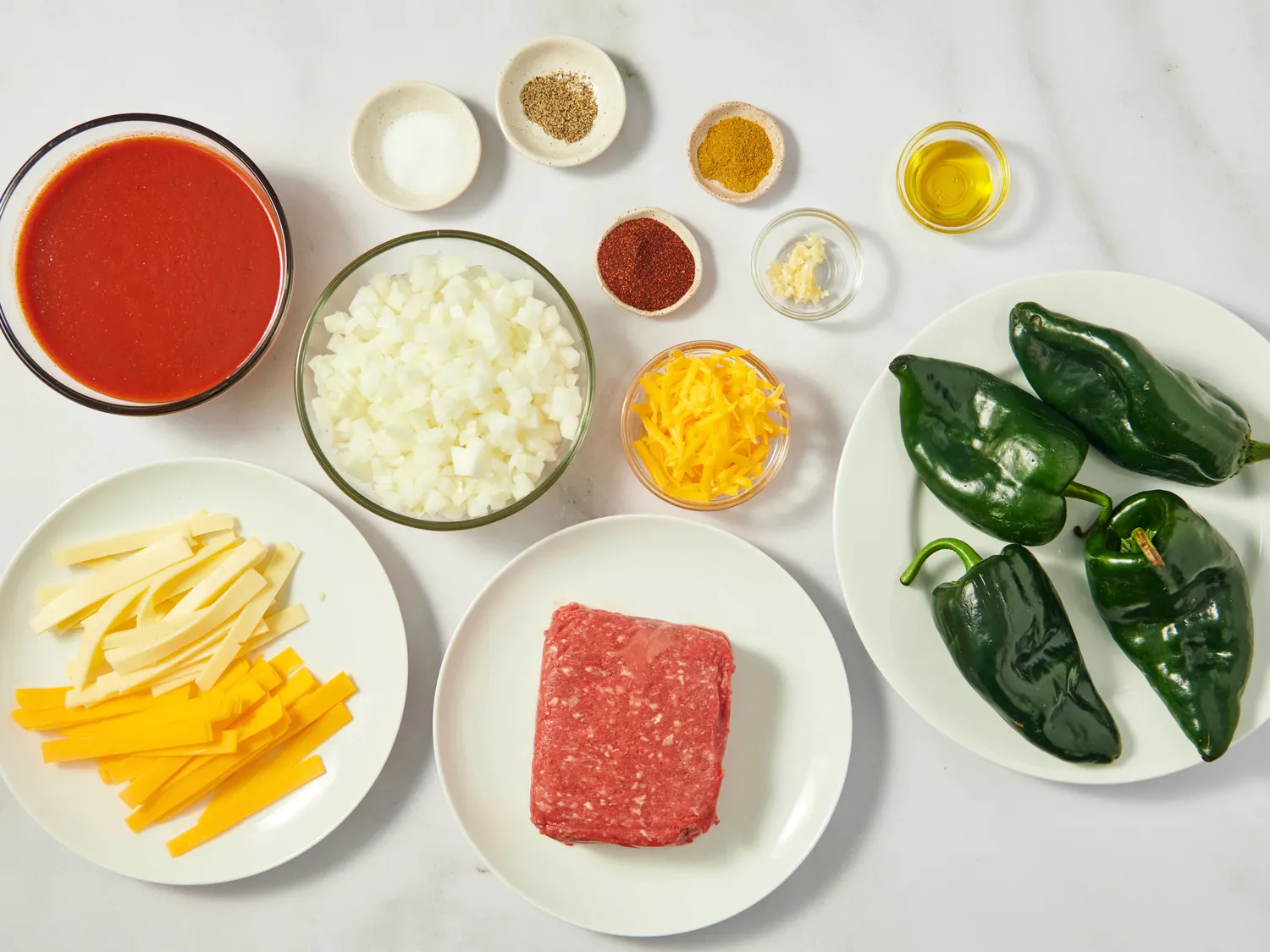Ingredients for stuffed poblano peppers including ground meat cheese poblano peppers seasonings and chopped onion