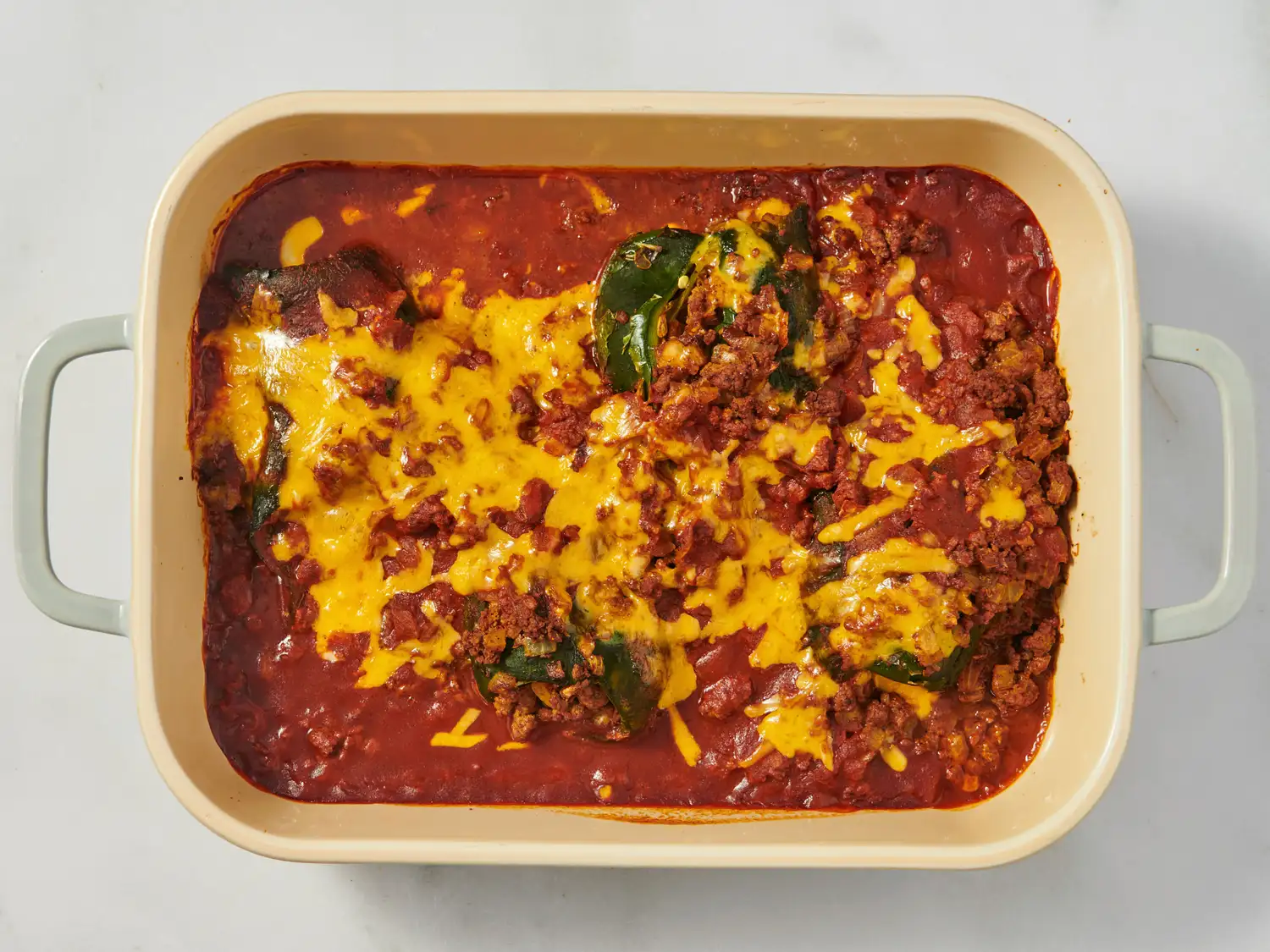 Stuffed poblano peppers topped with melted cheese in a baking dish