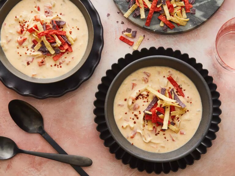 Close up on two large bowls of creamy chicken taco soup, topped with tortilla strips