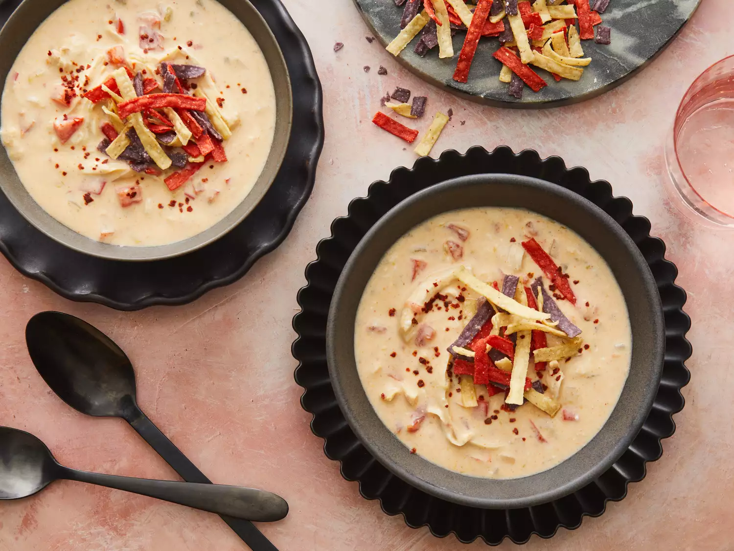 Close up on two large bowls of creamy chicken taco soup, topped with tortilla strips