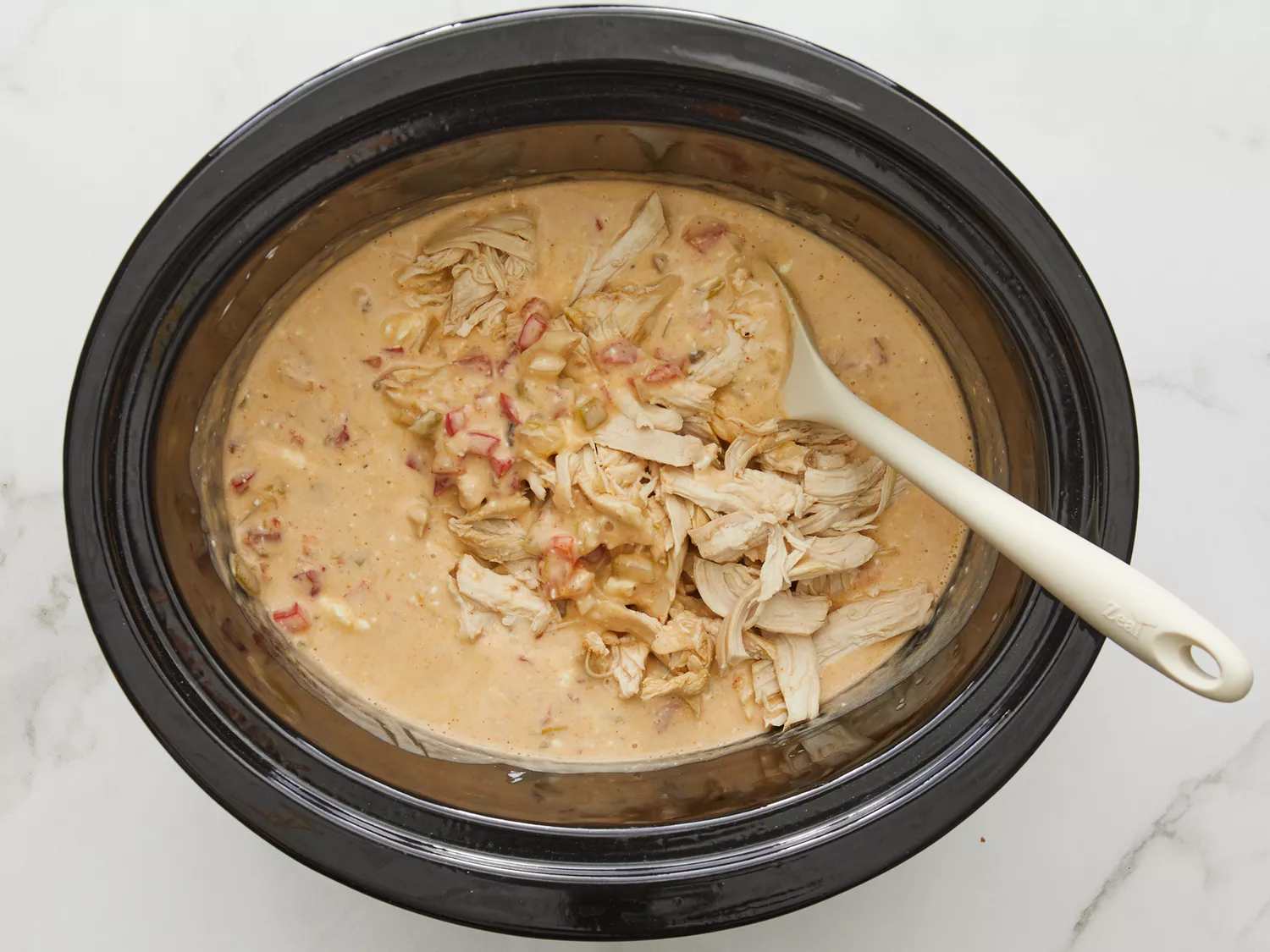shredded chicken and cream cheese being added to back into a crockpot. 
