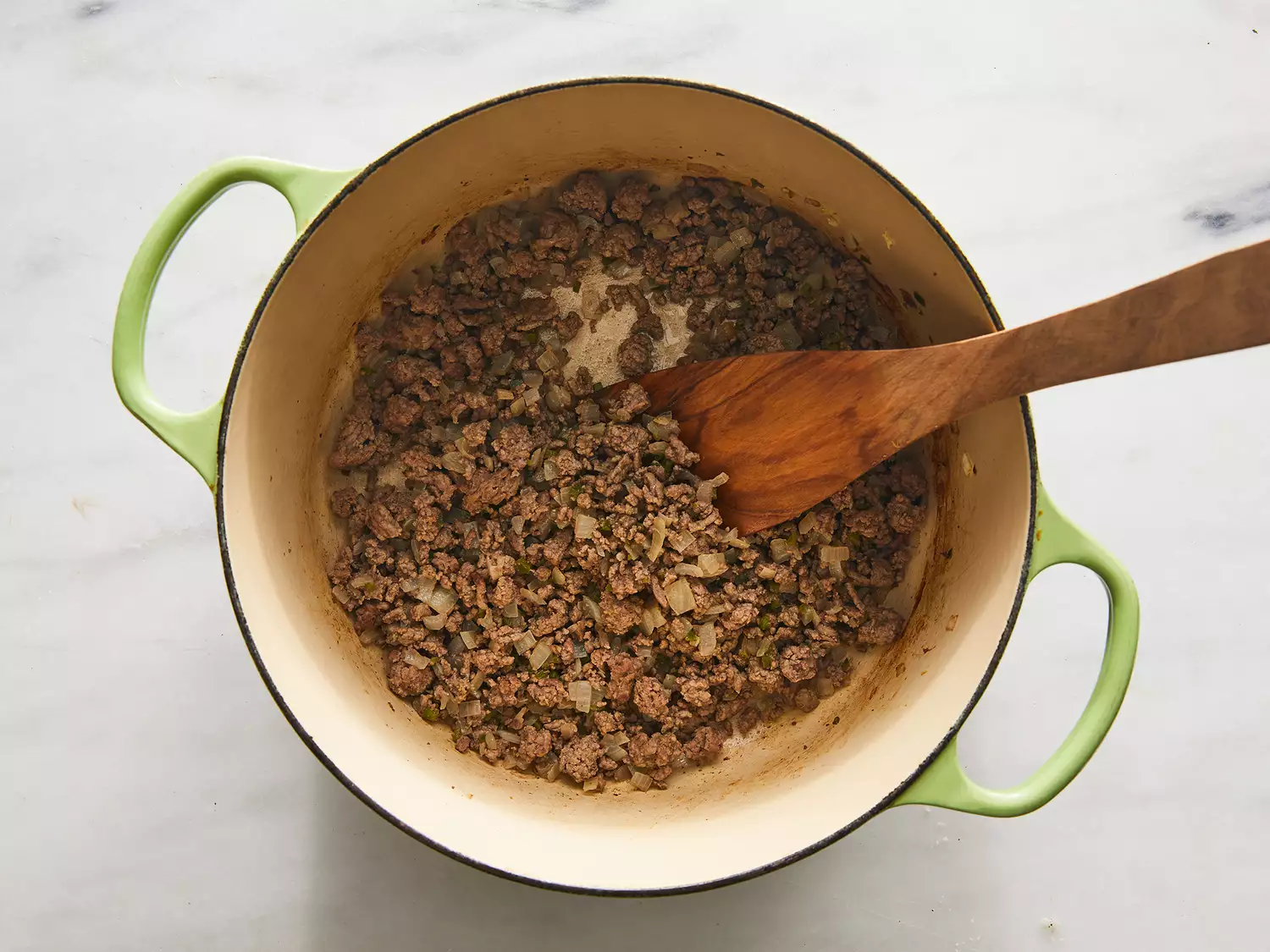Beef, onion and jalapeño cooking in a pot.