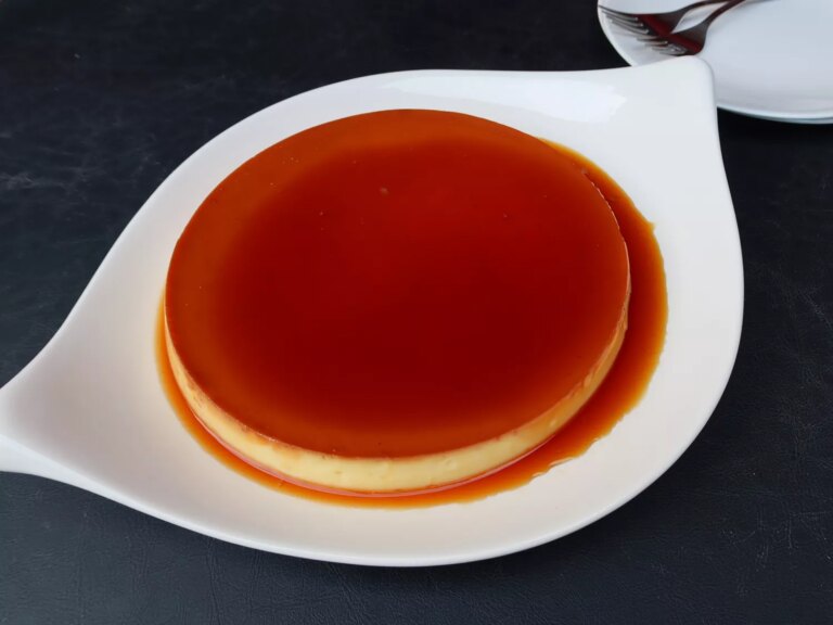 Instant pot bahn flan (vietnamese flan) on a white serving platter with a deeply colored caramel sauce pooling around the custard