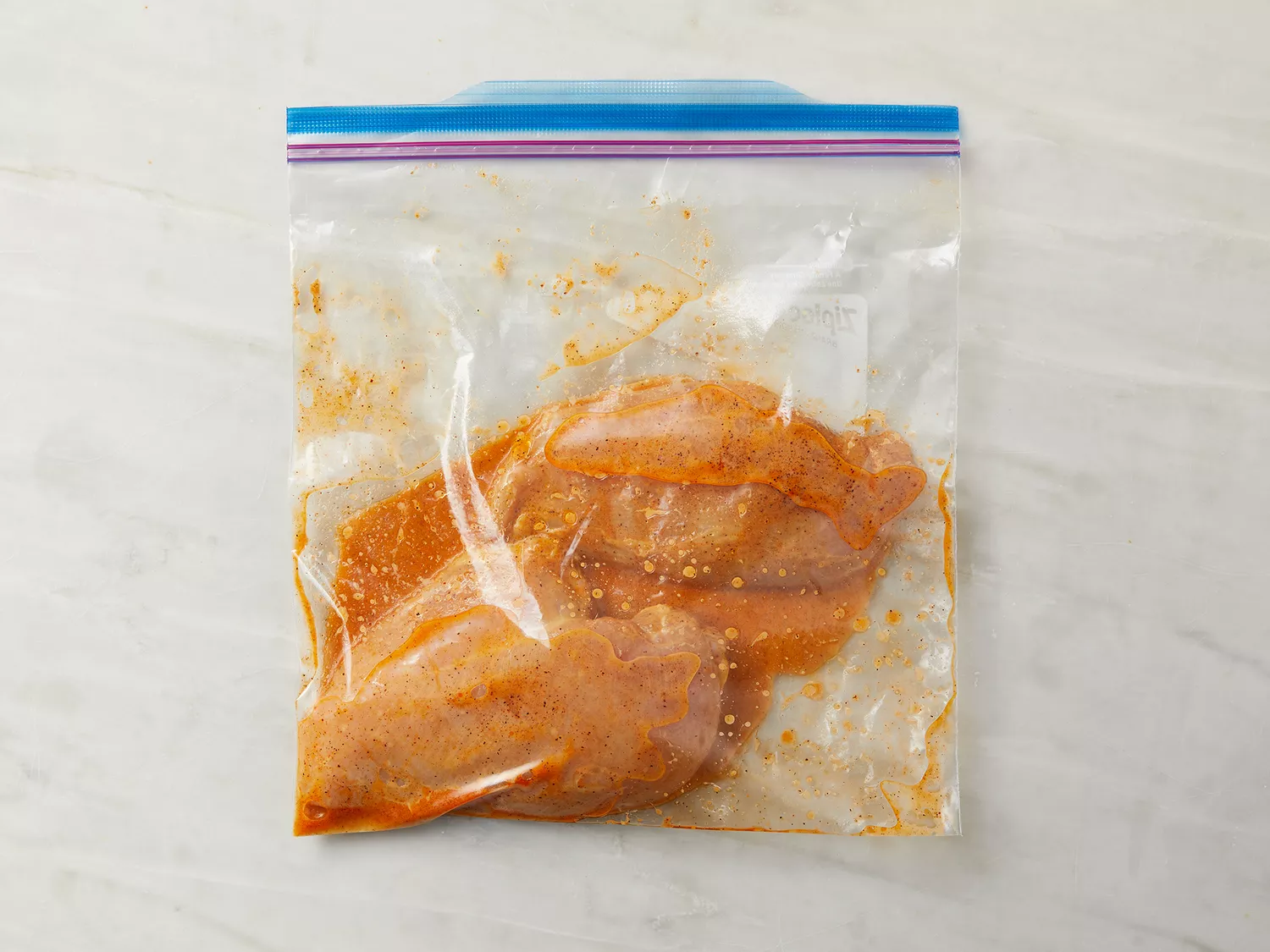 Chicken breasts in a resealable plastic bag with a marinade inside. 