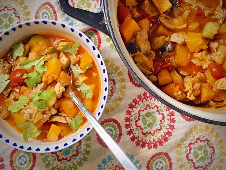 Calabaza squash and chicken in bowl garnished with cilantro and large pot on the side