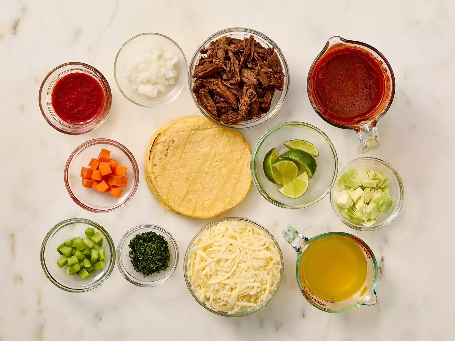 Ingredients for birria tacos arranged on a white surface.