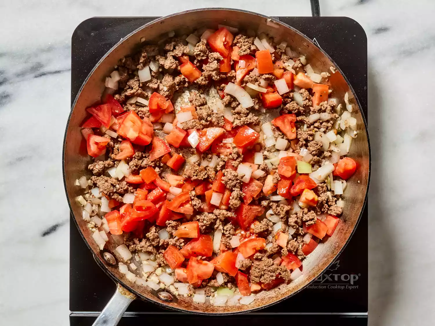 ground beef and vegetables cooking in a skillet 