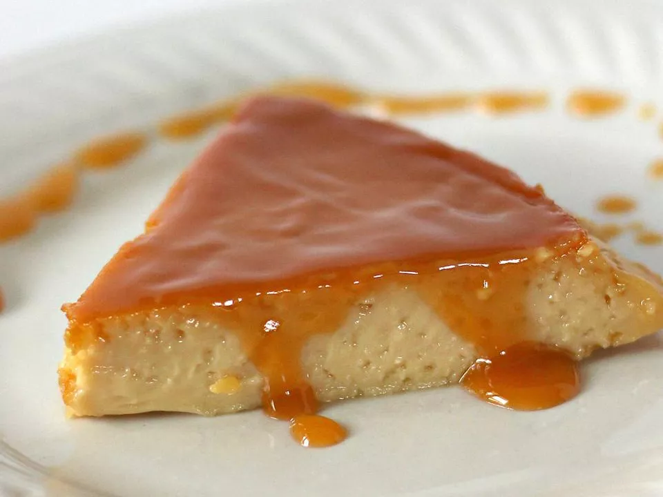 Close up view of a slice of creamy spanish flan on a white plate