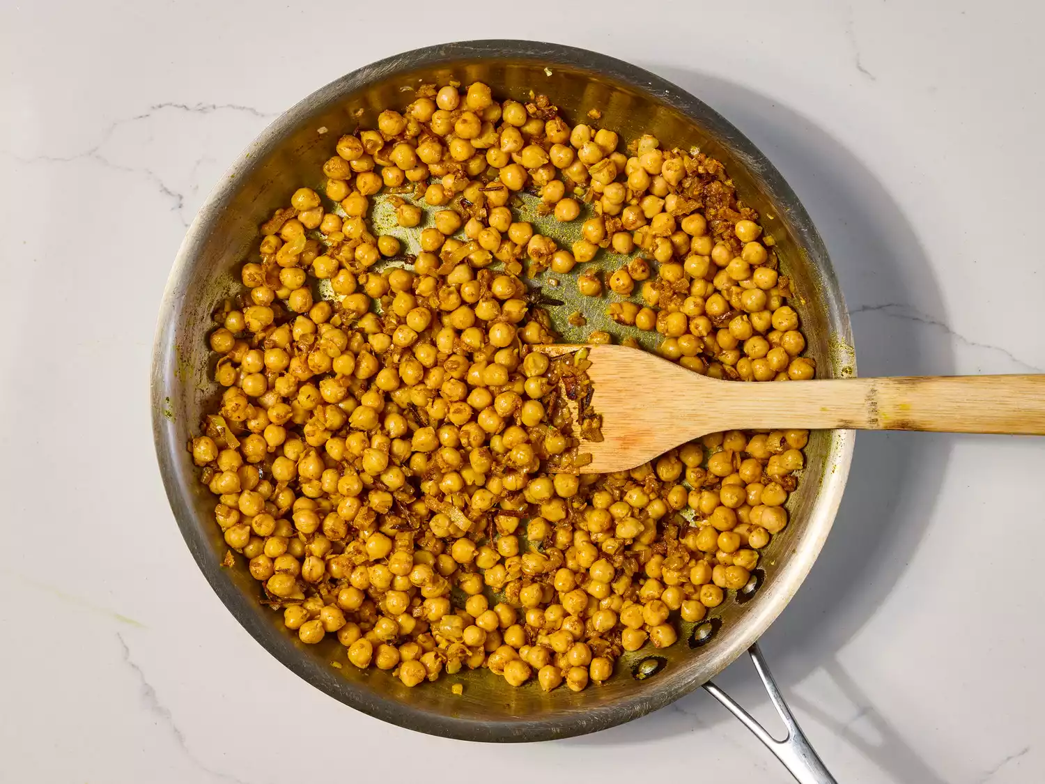 Chickpeas and spices simmering in a pan with onions.