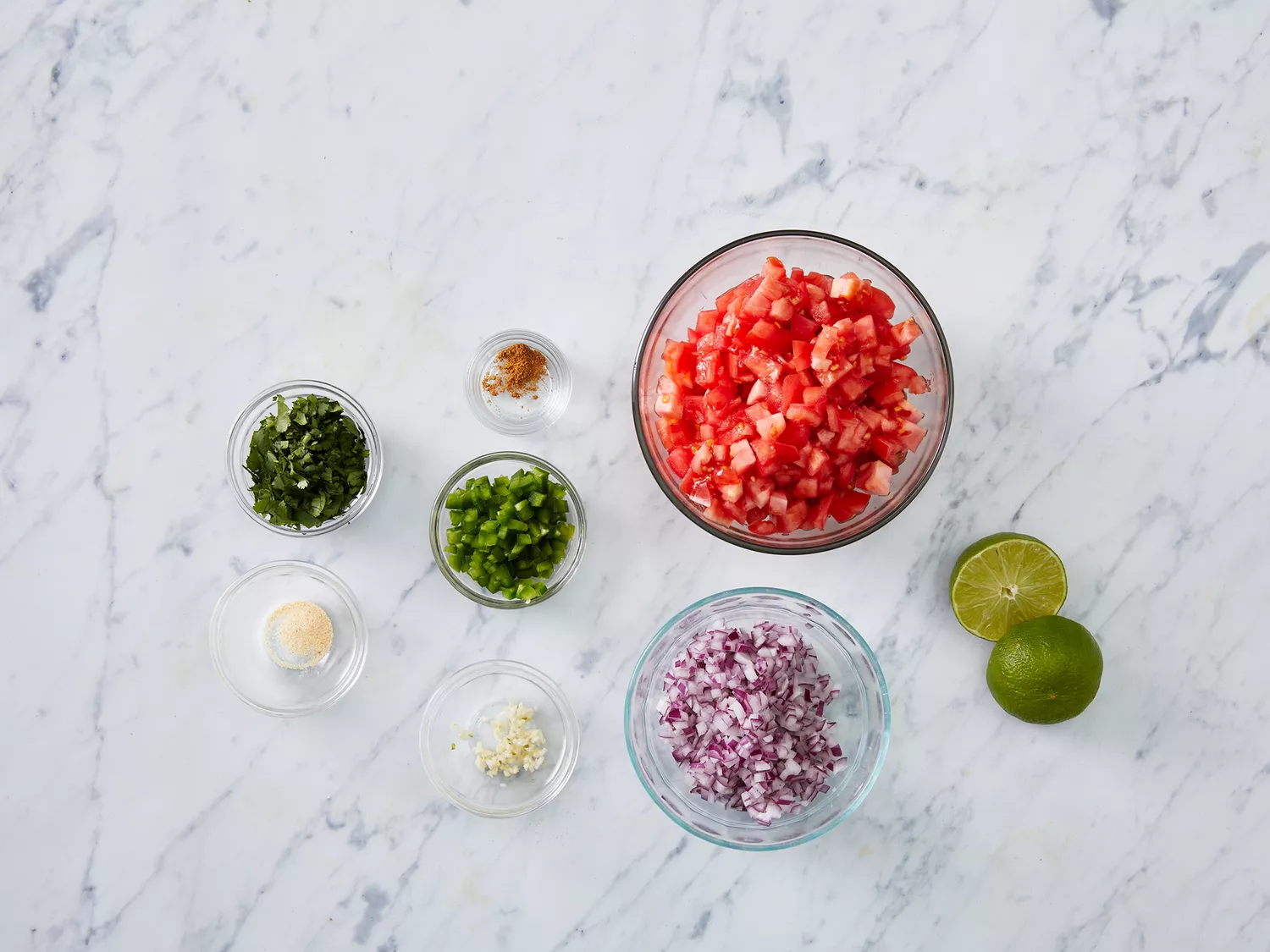 Overhead of pico de gallo ingredients in various bowls. 