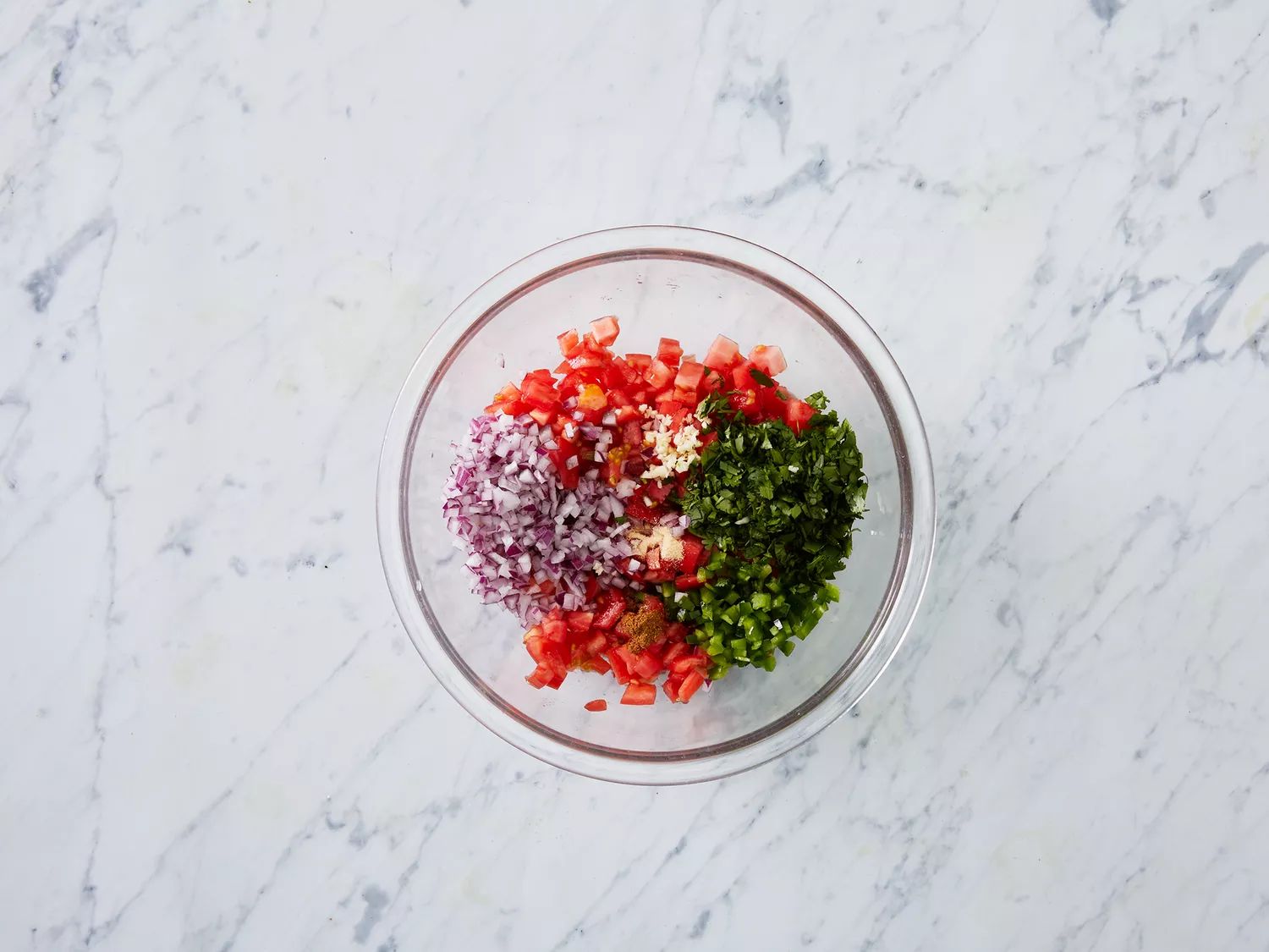 Overhead of unmixed pico de gallo ingredients in a bowl. 