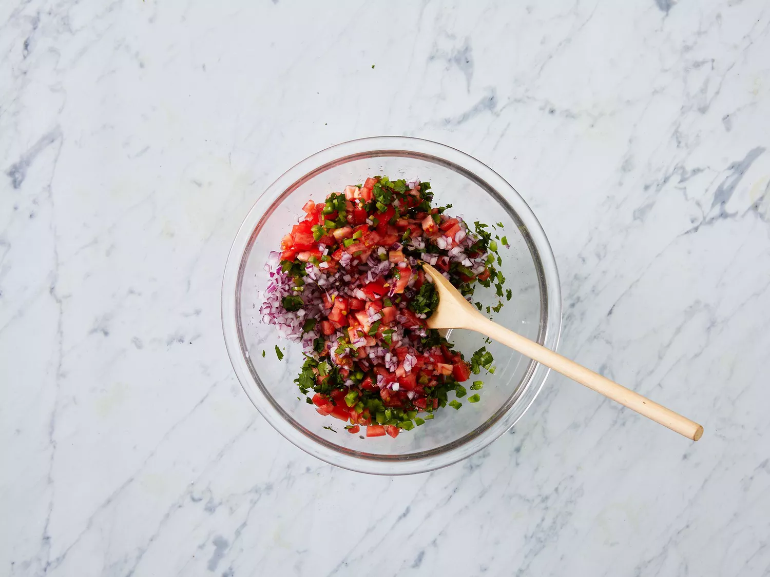 Overhead of pico de gallo being stirred in a bowl. 