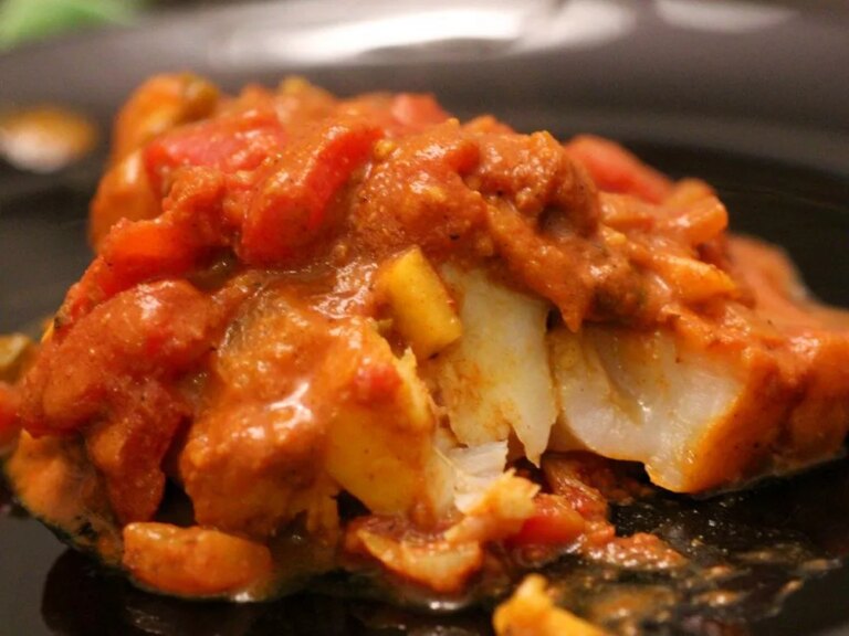 Close up view of cod curry on a black plate
