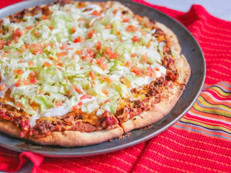 Taco pizza topped with lettuce and tomatoes