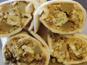 Close up view of a pile of bacon, potato, and egg tacos
