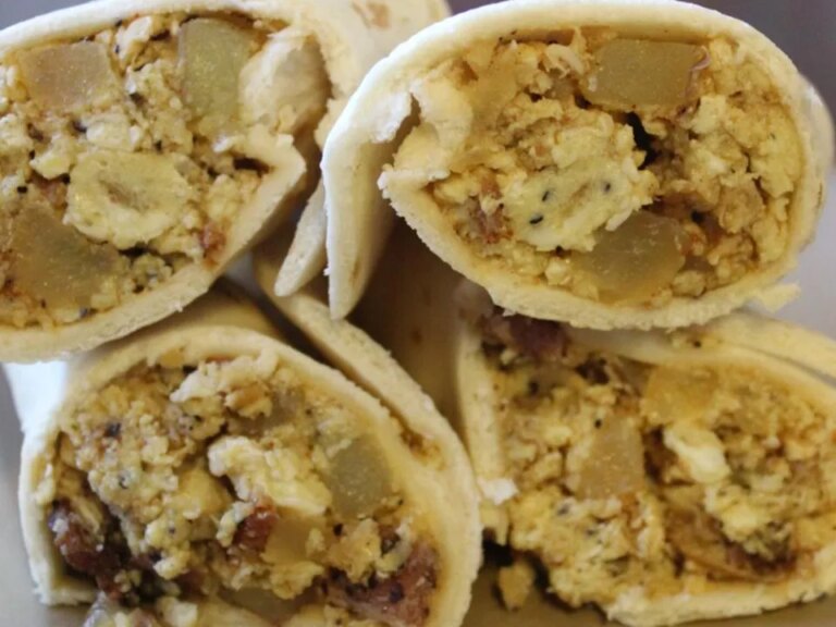 Close up view of a pile of bacon, potato, and egg tacos