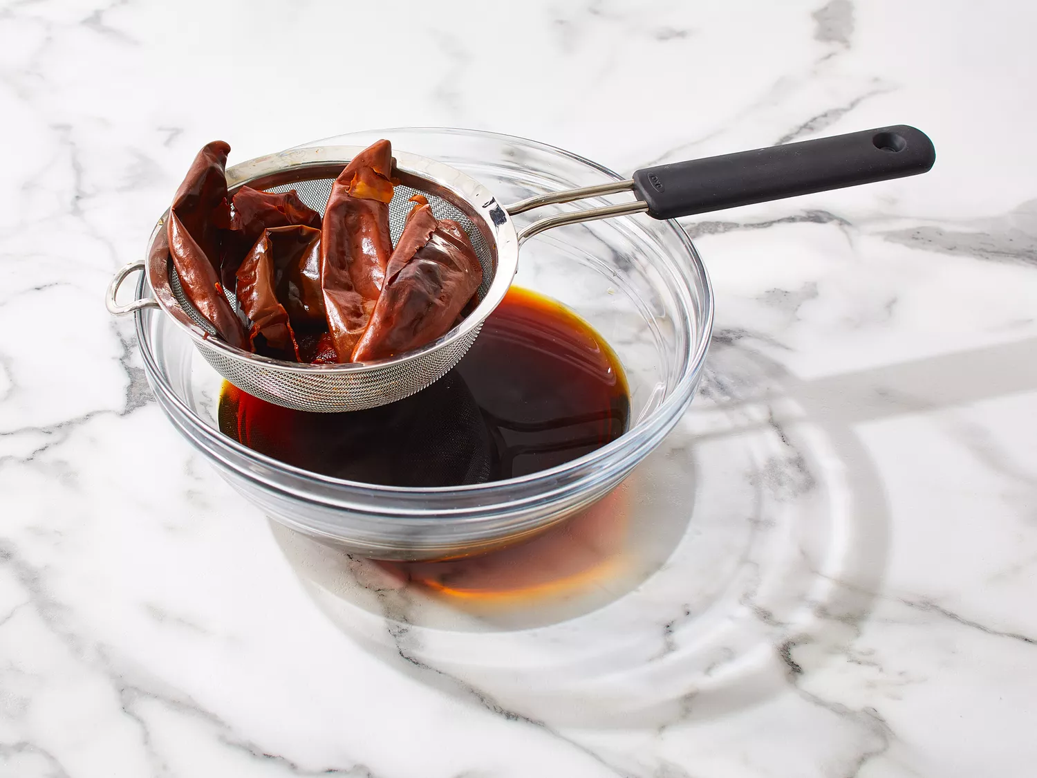 Liquid from the chiles strained into a bowl.