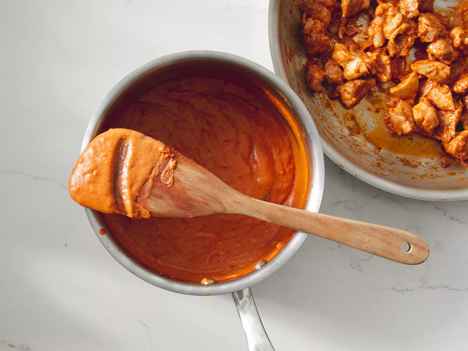 A few spoonfuls of sauce added to chicken in skillet.
