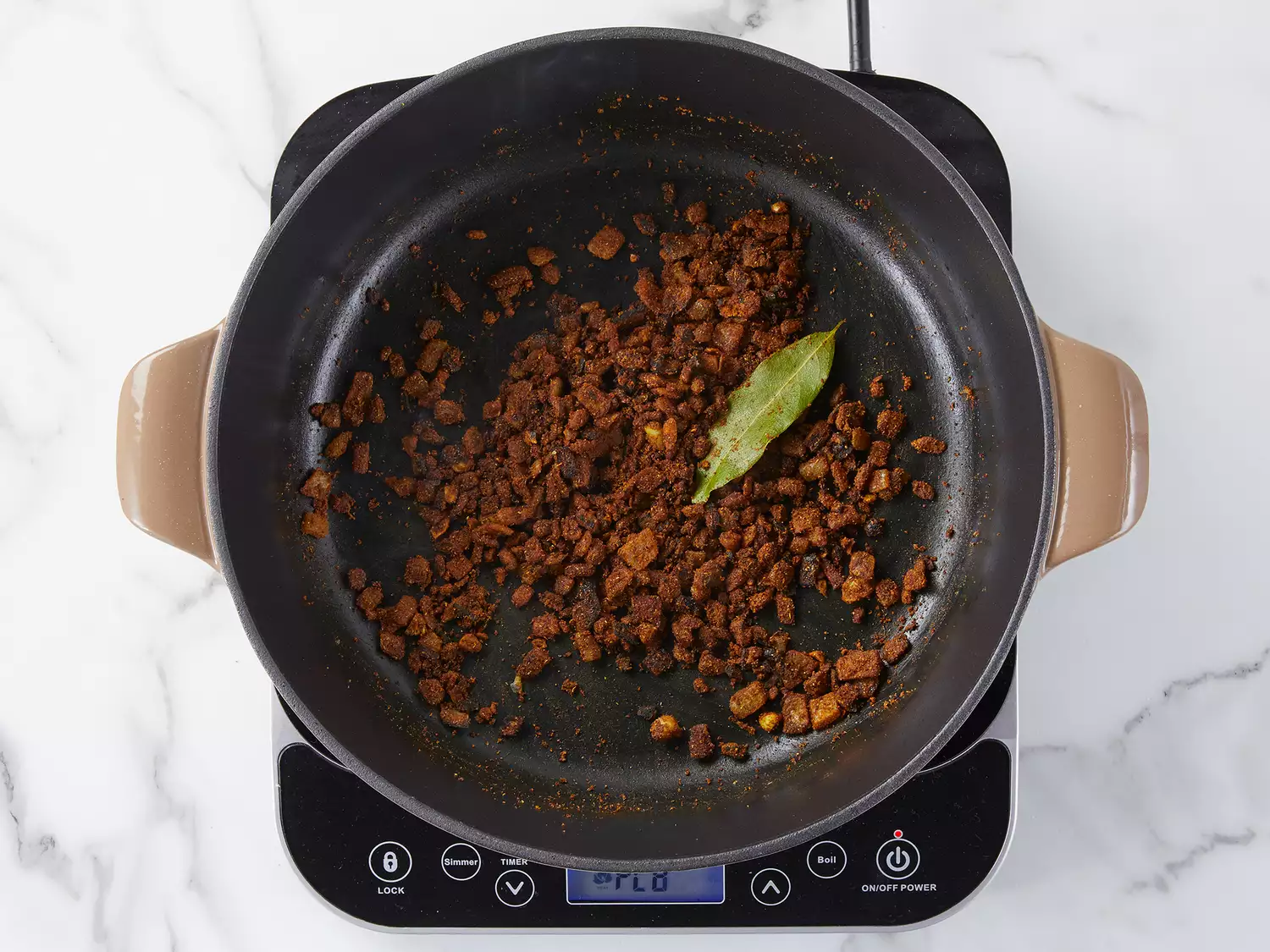Various spices and seasonings being mixed with onions and cooking on a skillet. 