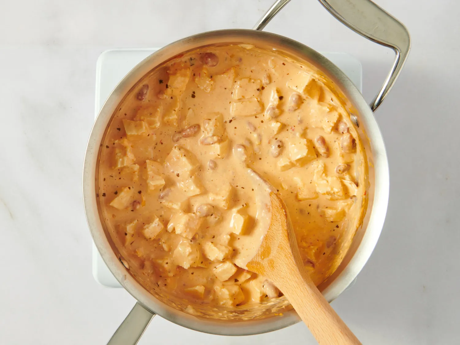 Cooking creamy sauce with diced ingredients stirred in a saucepan