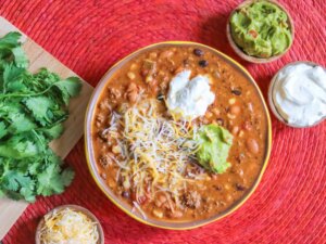Cheesy taco soup topped with guacamole and sour cream