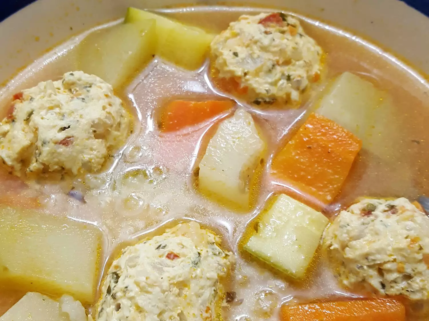Close up view of mexican chicken meatball soup (sopa de albóndigas de pollo) with carrots and potatoes, in a bowl