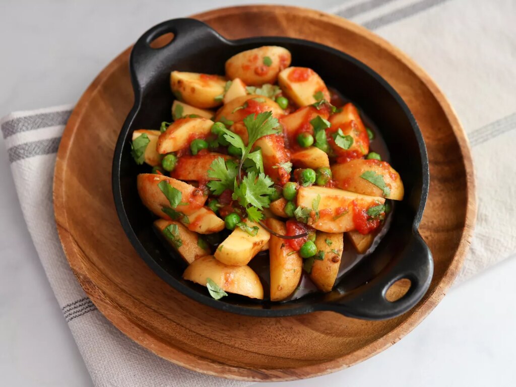 Indian potatoes and peas garnished with cilantro in round cast iron dish