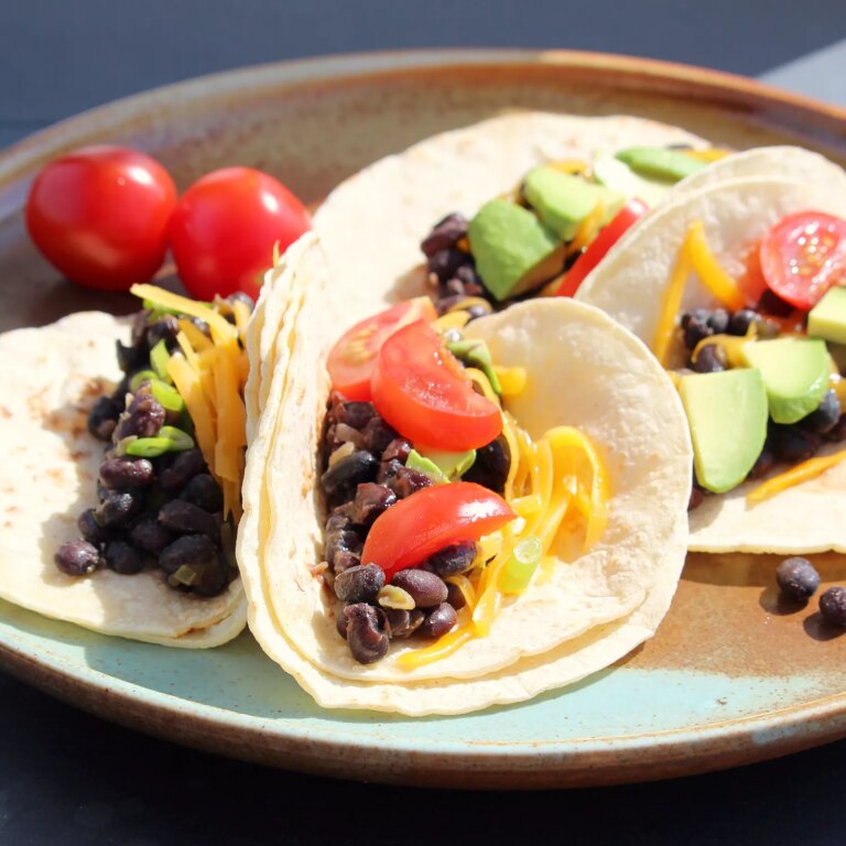 Close up view of black bean tacos with tomatoes and avocados on a plate