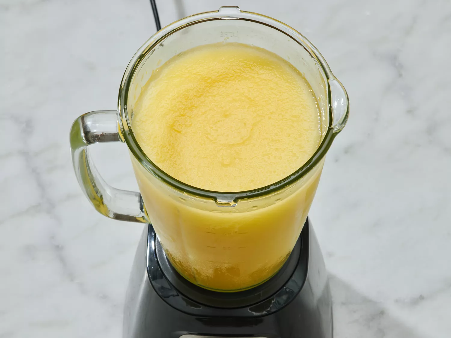 A blender jar containing a blended beverage, placed on a countertop