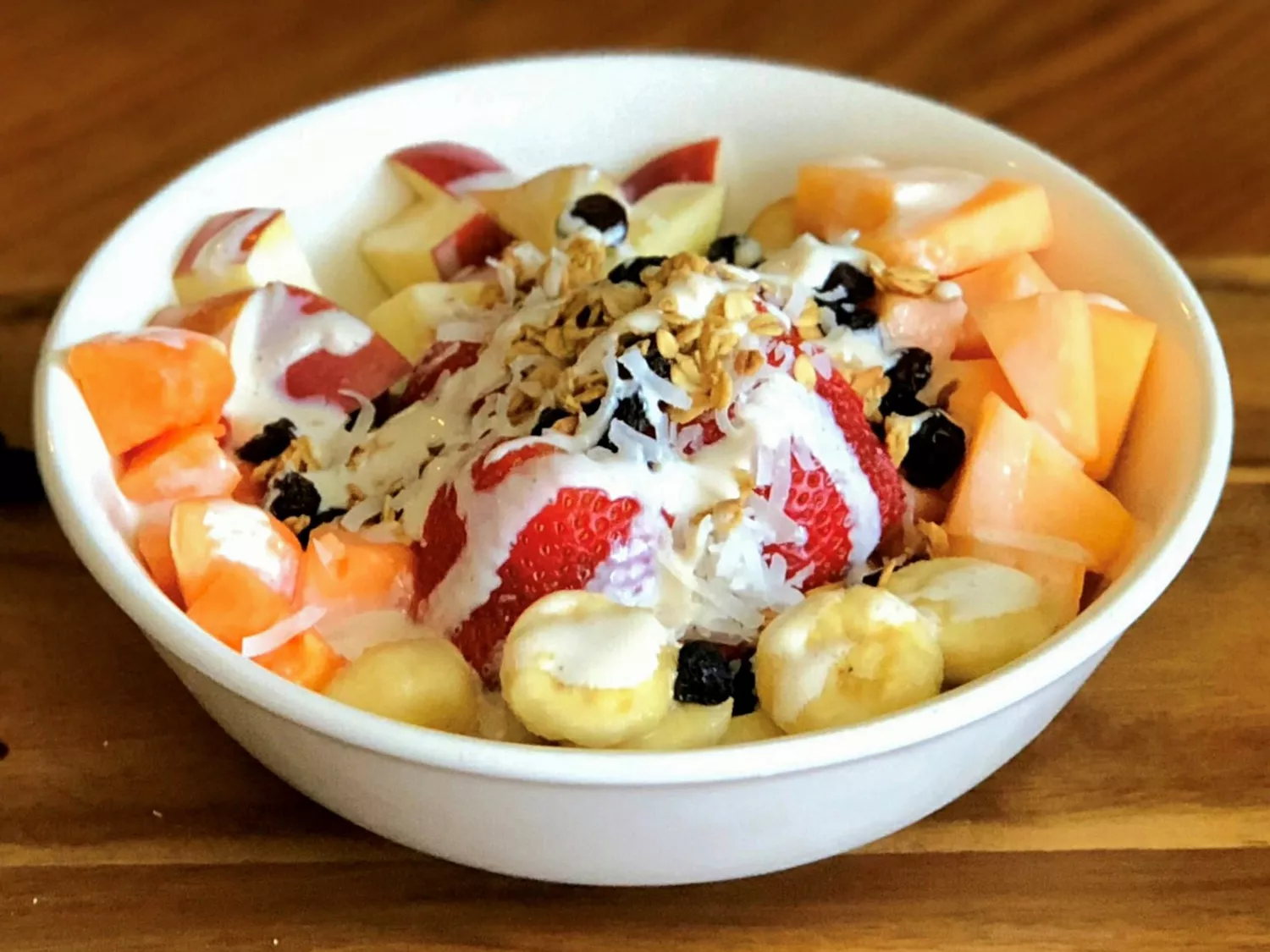 Close up view of a mexican fruit bowl garnished with shaved coconut and raisins in a bowl