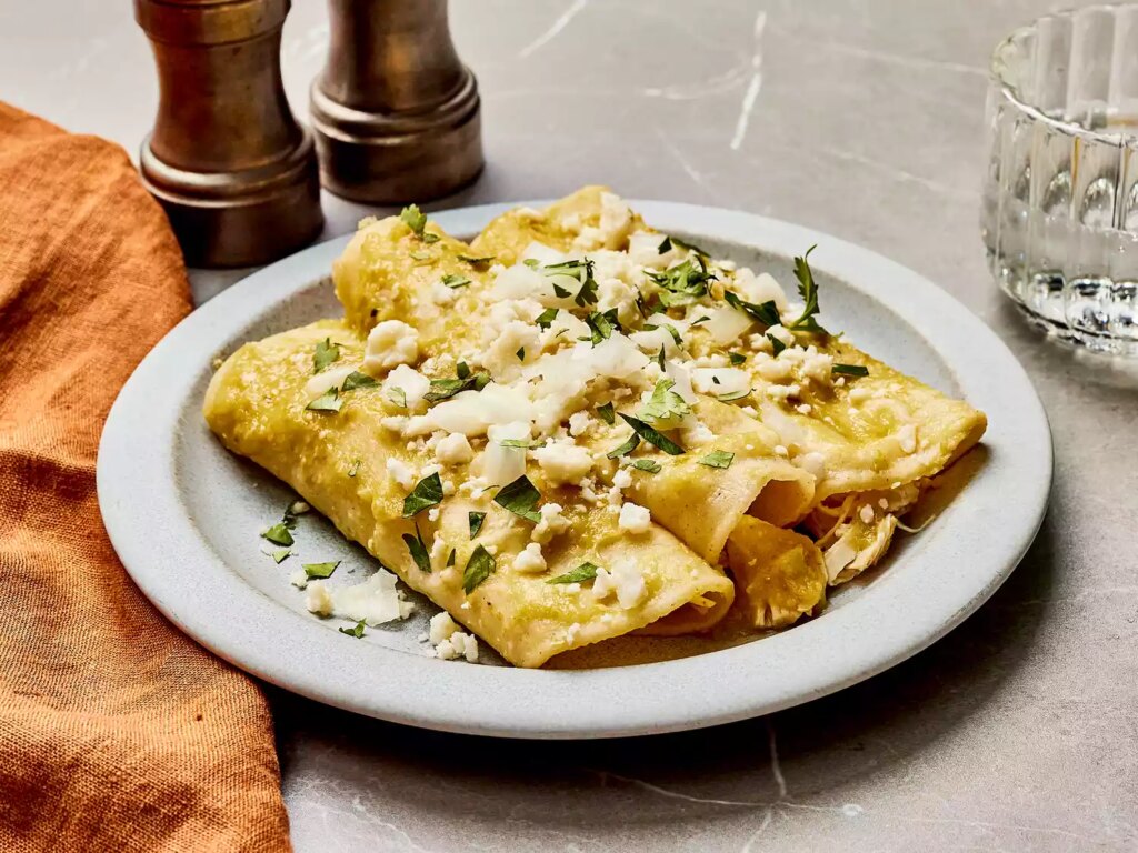Authentic enchiladas verdes garnished with cheese and herbs on a plate