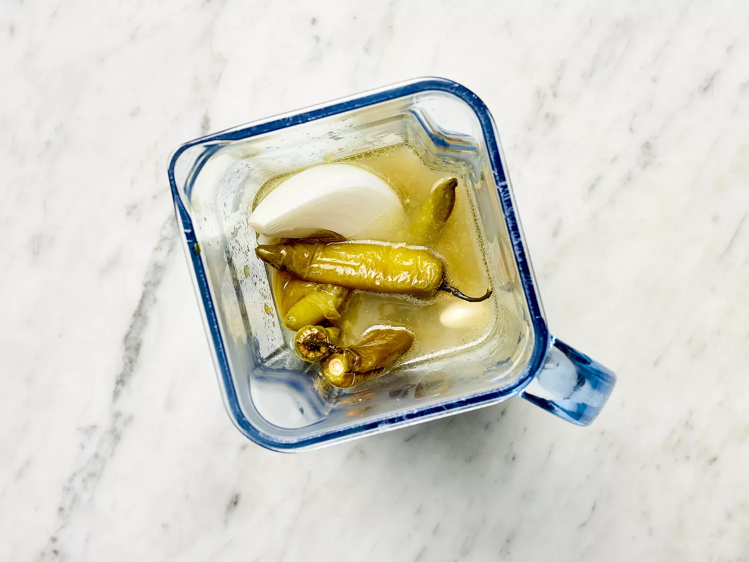 Tomatillos and serrano peppers in a blender with an onion 