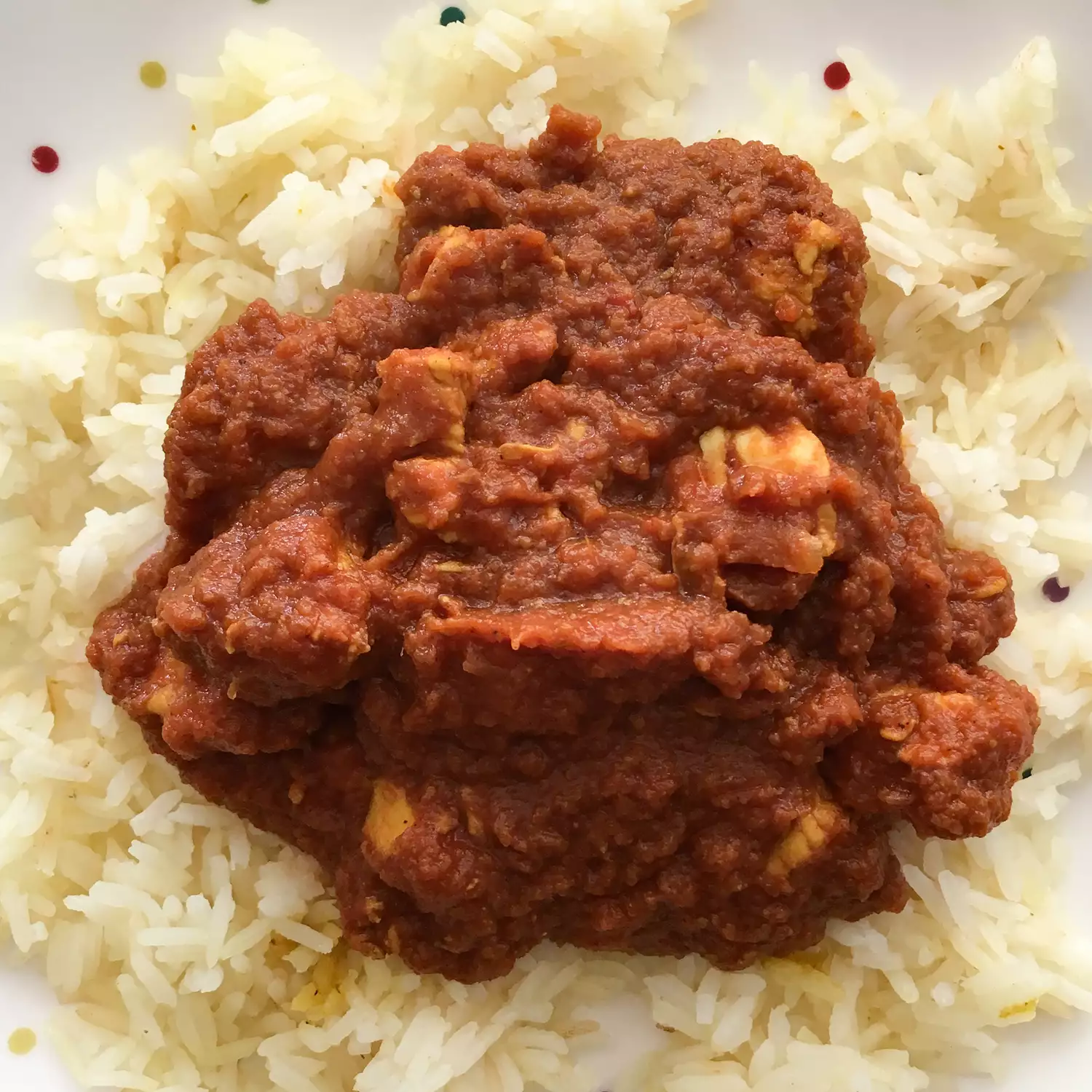 close up view of Indian Tomato Chicken over white rice on a plate